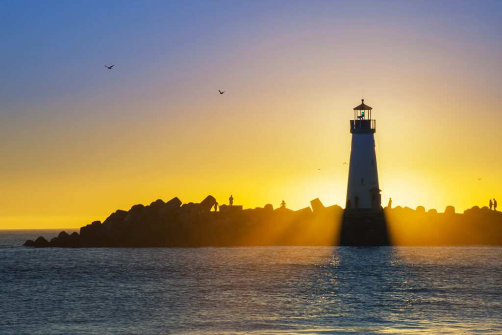 a lighthouse in the ocean during sunset
