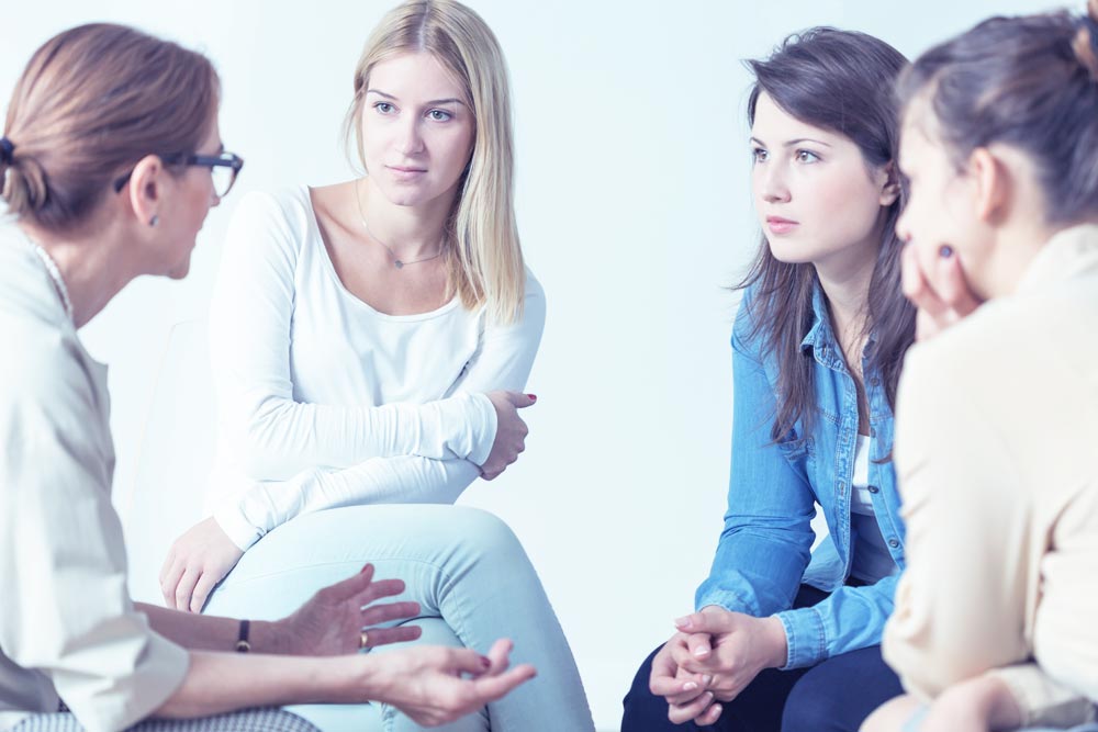 young women listening to a psychologist during their group therapy
