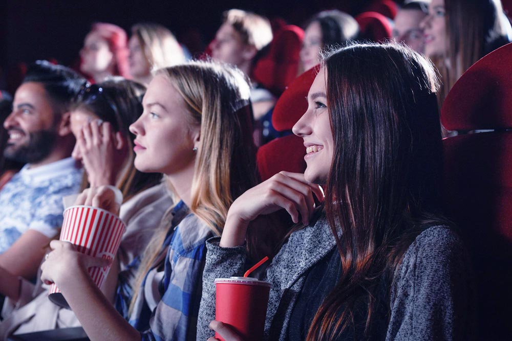 a female watching movie in cinema with friends
