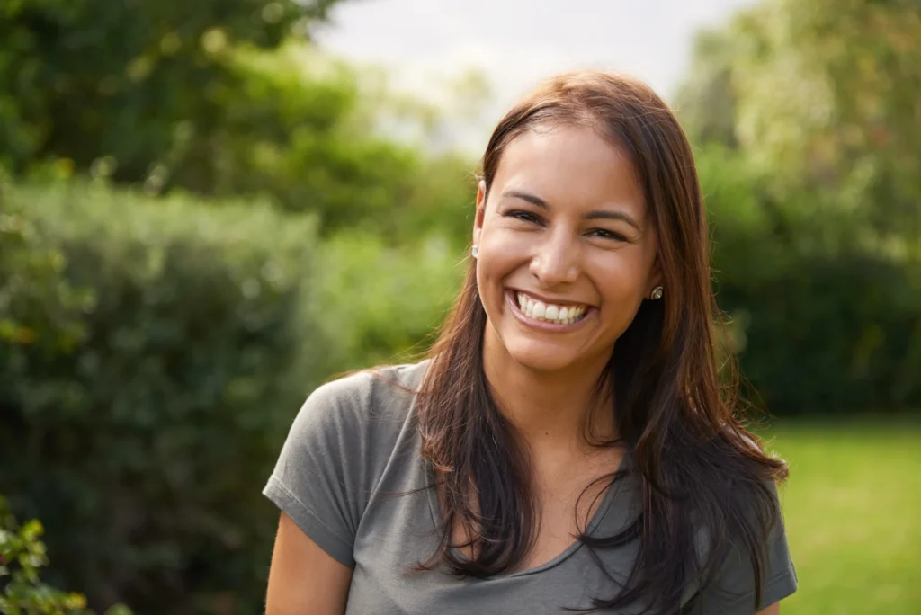 Smiling person in a calm outdoor setting.